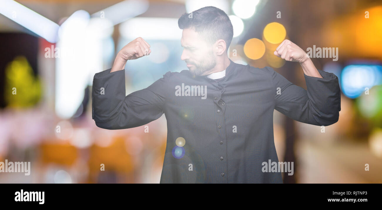 Young Christian priest over isolated background showing arms muscles smiling proud. Fitness concept. Stock Photo
