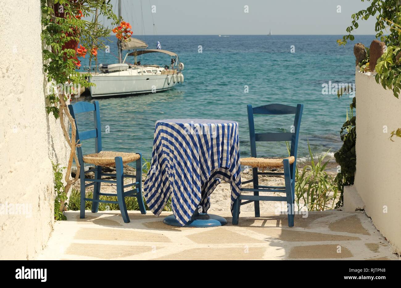 Traditional Greek blue table and chairs by the Aegean sea, Aegina island Stock Photo