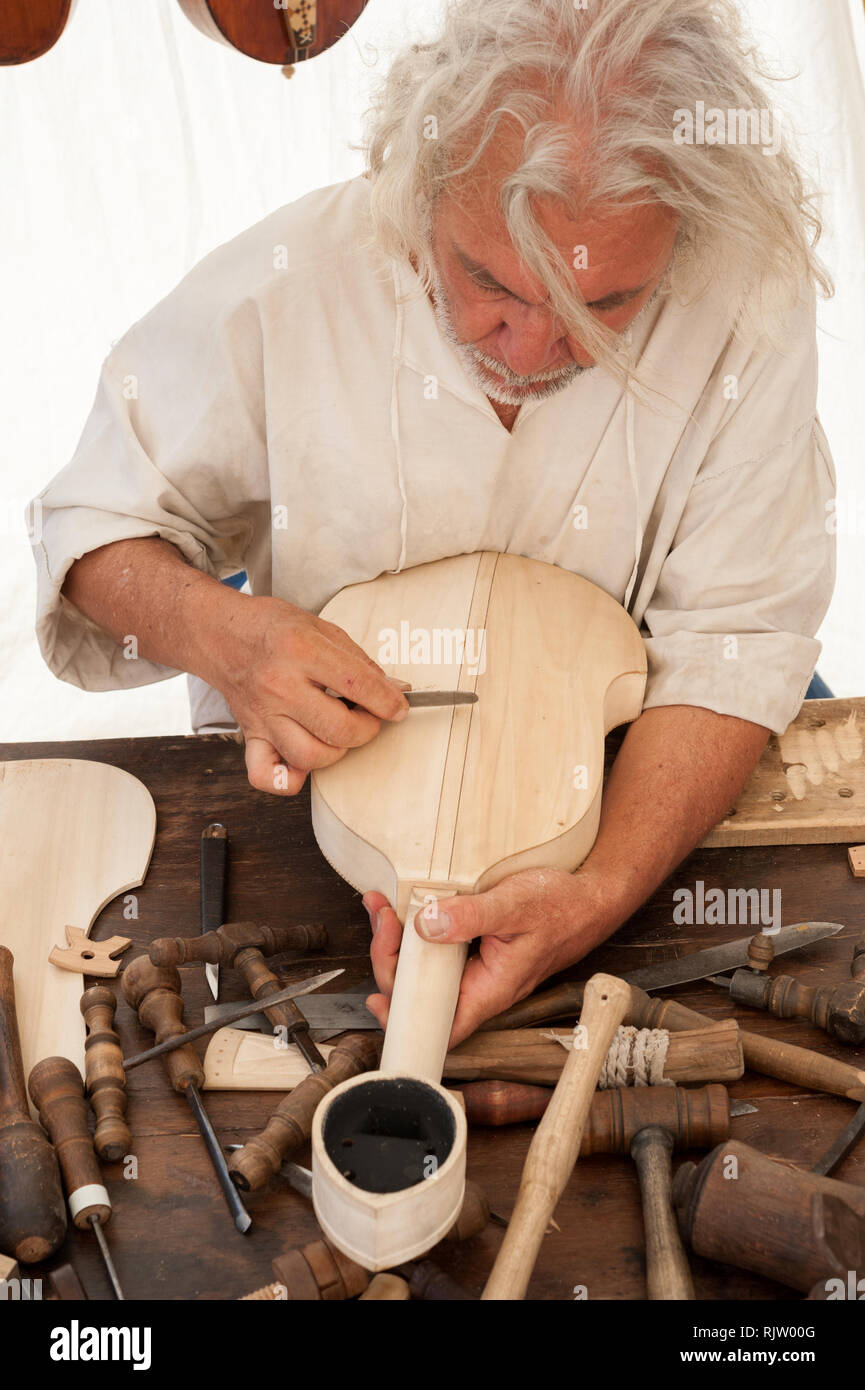 Luthier working on the creation of a stringed instrument. Various tools and instrument are placed on the workbench Stock Photo