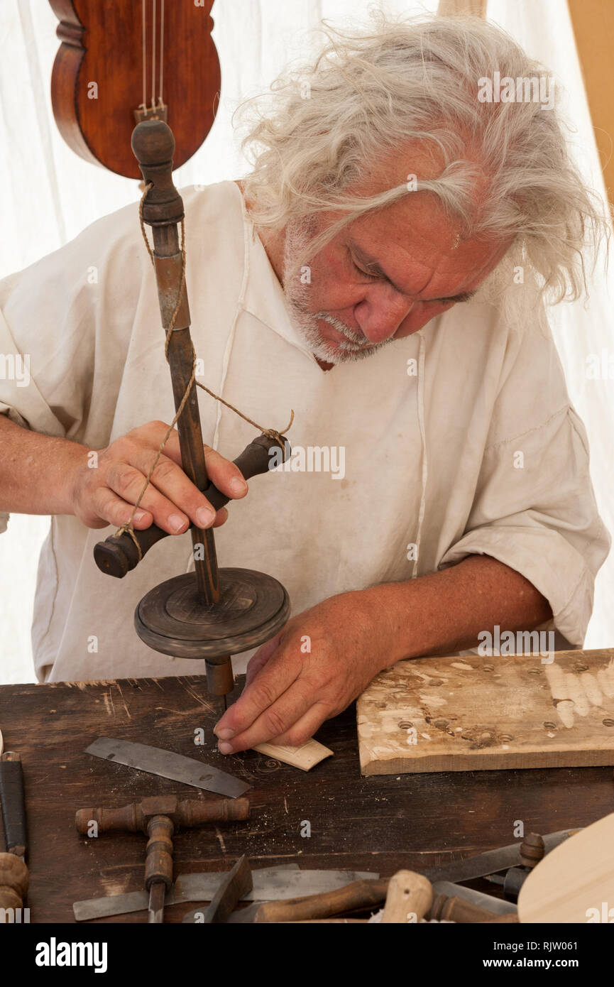 Luthier working on the creation of a stringed instrument. He uses an old manual drill Stock Photo