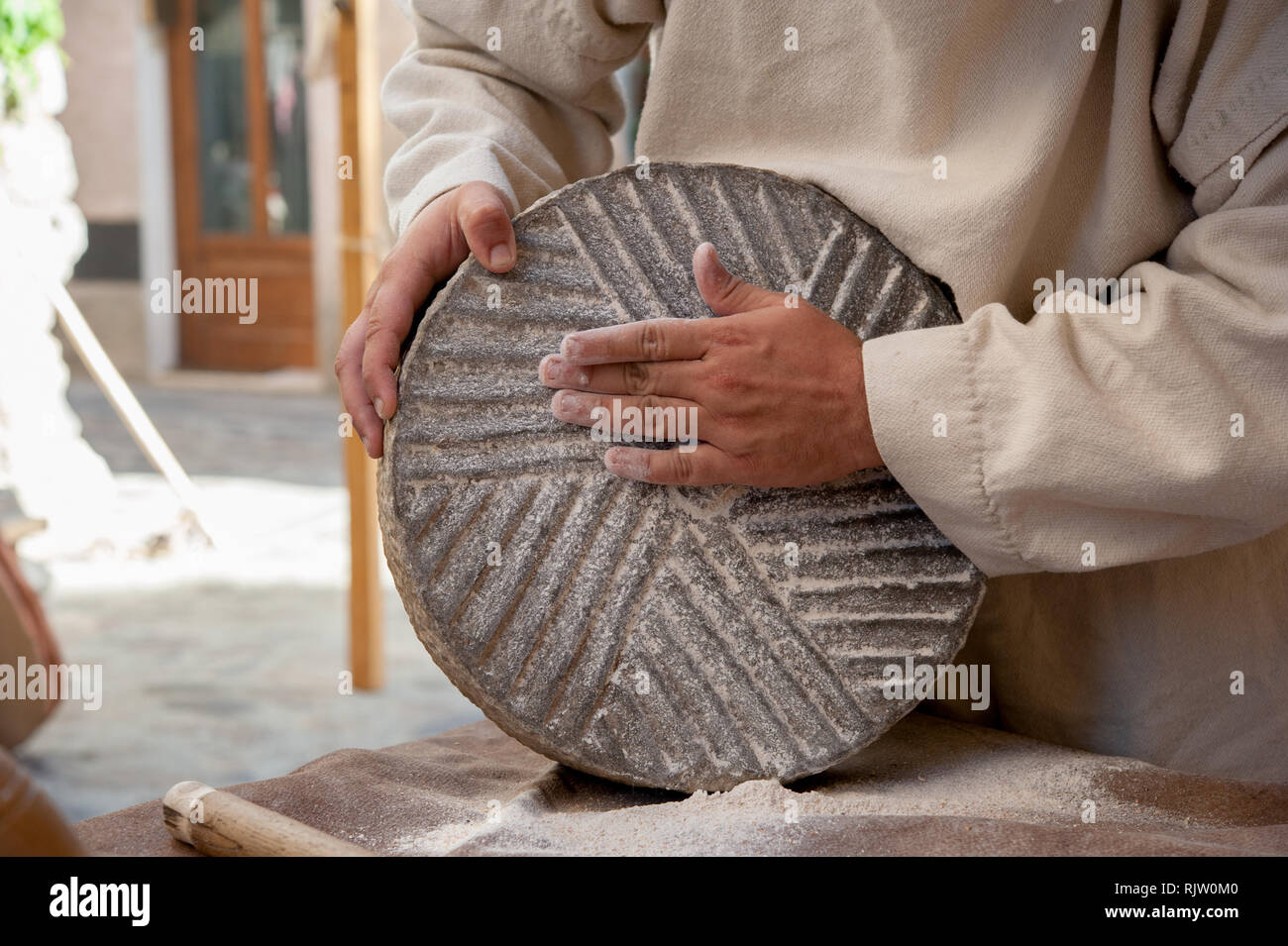 the miller remove the flour from old grinding stone Stock Photo
