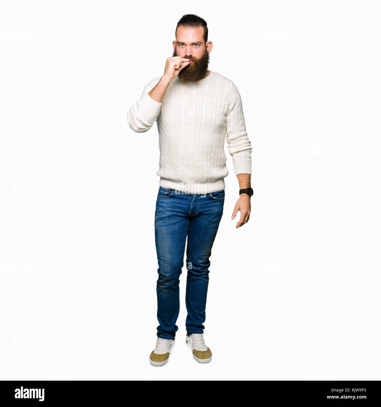 Young hipster man wearing winter sweater mouth and lips shut as zip with fingers. Secret and silent, taboo talking Stock Photo