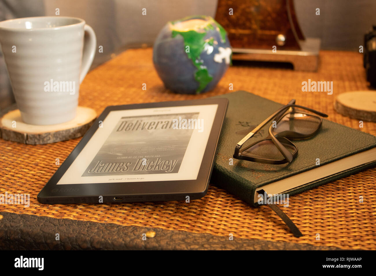 Side table with E-Book, coffee mug, eye glasses and candle. Stock Photo