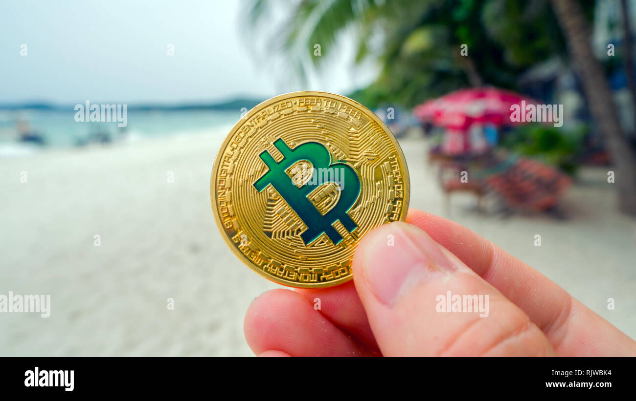 Hand holding golden bitcoin on the beach, on the background of sea wave.  Bitcoin is a modern way of exchange this crypto currency is a convenient  mean Stock Photo - Alamy