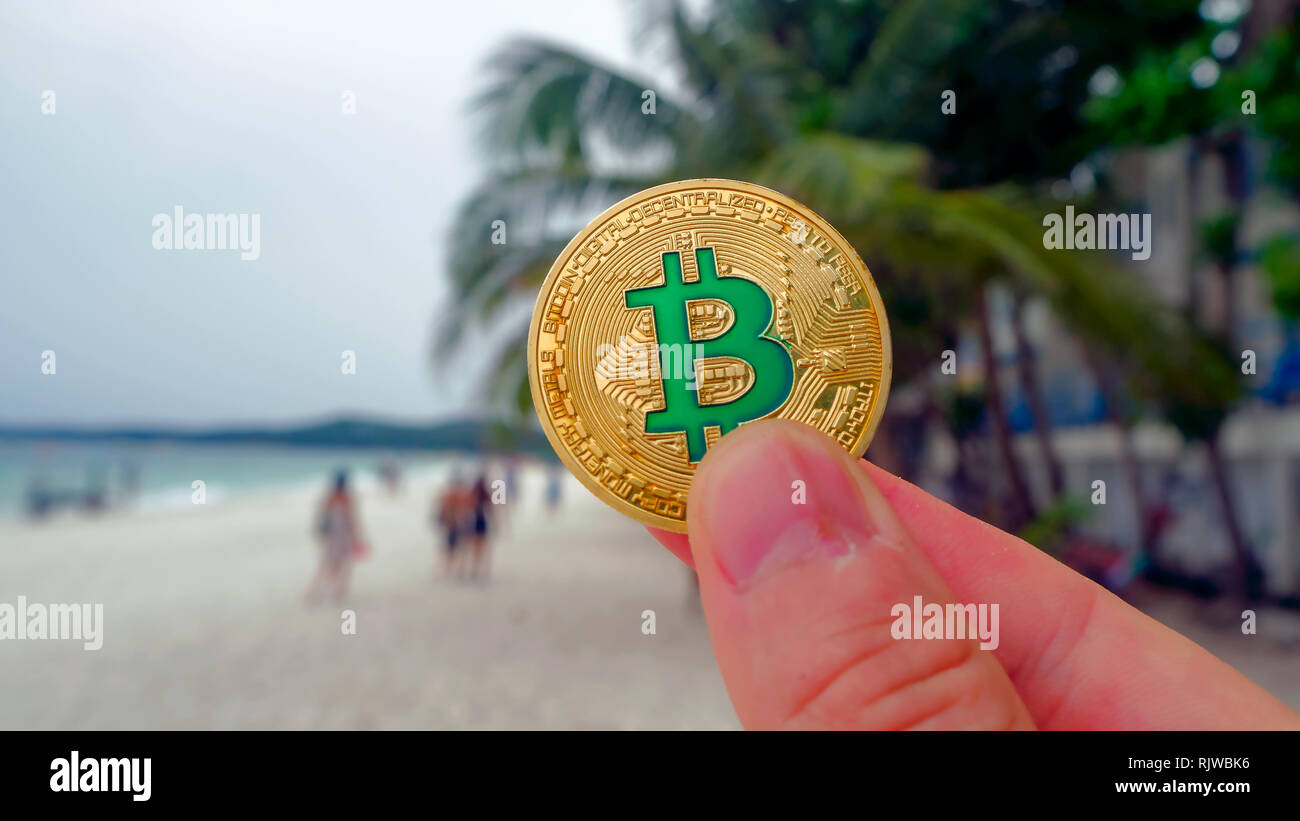 Hand holding golden bitcoin on the beach, on the background of sea wave.  Bitcoin is a modern way of exchange this crypto currency is a convenient  mean Stock Photo - Alamy