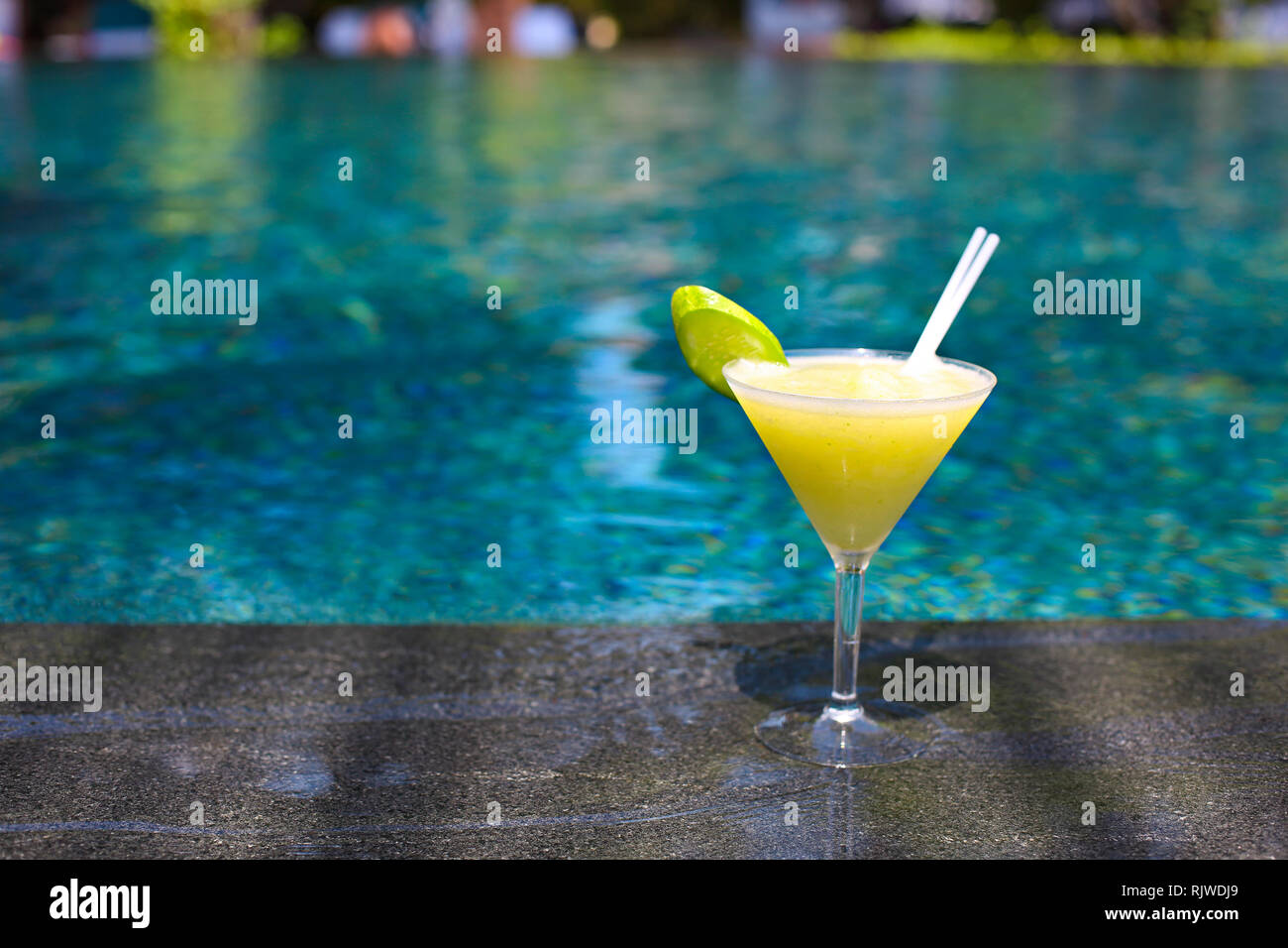 Cucumber drink cocktail by the pool with turquois water Stock Photo