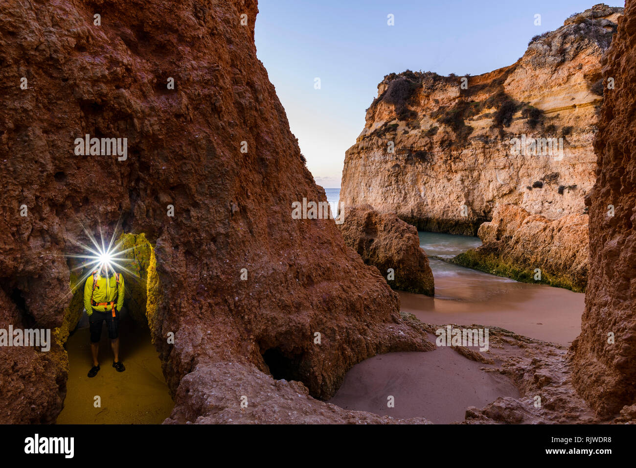 Man standing by cliff with illuminated headlamp, Alvor, Algarve, Portugal, Europe Stock Photo