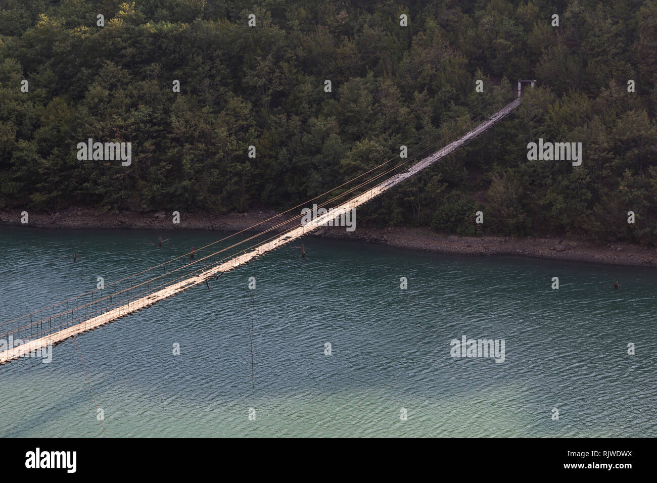Albania: Decaying Hanging or suspension bridge with loose wires and broken wooden planks Stock Photo