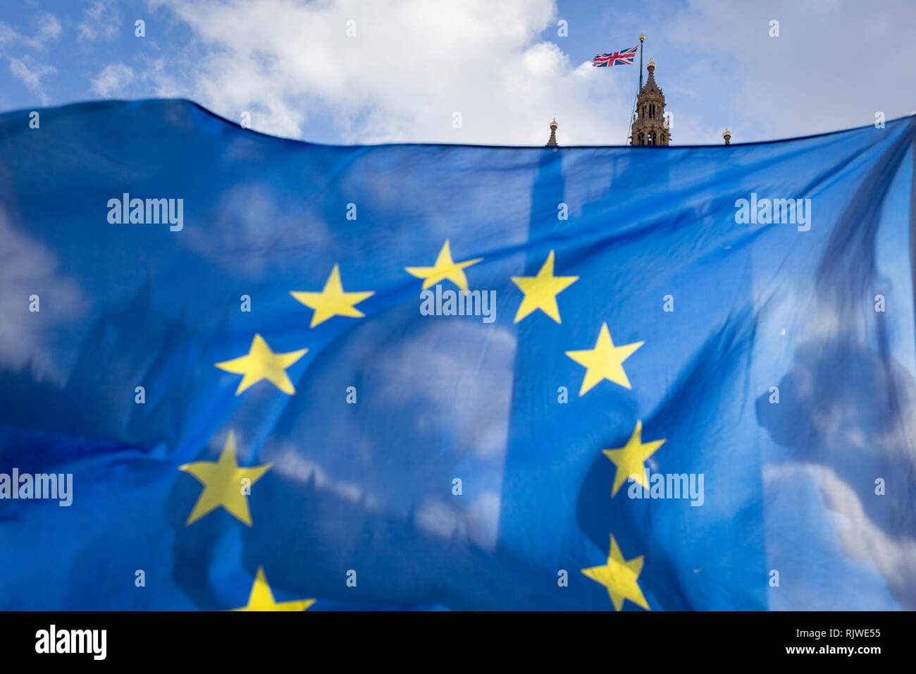 As Prime Minister Theresa May negotiates further Britain's exit from the European Union in Brussels, the UK parliament is seen through the yellow stars of the EU flag, flying as part of an anti-Brexit protest opposite the Houses of Parliament, on 7th February 2019, in Westminster, London England. Stock Photo