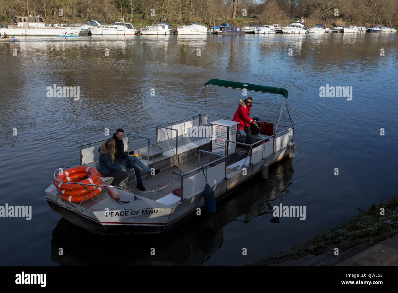 Two passengers on Hammerton's Ferry, cross the river Thames between Marble Hill House on the north bank, and Ham on the southern bank, on 3rd February 2019, in London, England. Hammertons Ferry was originally opened in 1908 by Walter Hammerton and its current owners are Mr & Mrs Francis Spencer in July, 2003. The whole family are currently involved in all aspects of the business, however the daily running of the Ferry is by father & son, Francis & Andrew Spencer. Hammerton's is a pedestrian and cycle ferry service across the River Thames in the London Borough of Richmond upon Thames, London Stock Photo
