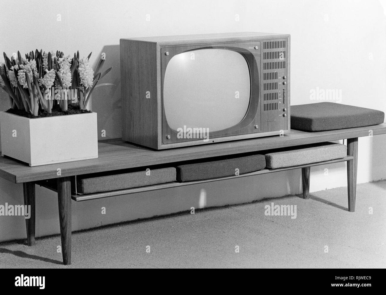 Television in the 1960s. A tv set from the dutch manufacturer Philips 1960. In home decorating new and suitable furniture focused on and around the tv, as this tv bench with practical cushions to use when sitting in front of the tv. Stock Photo
