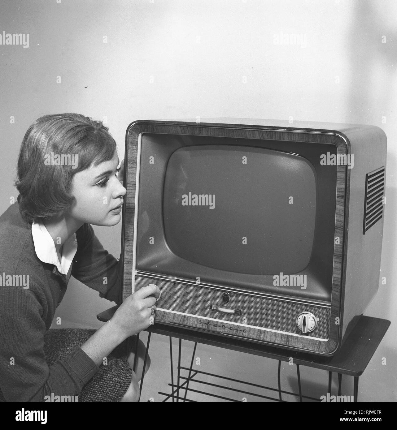 Television in the 1950s. A young woman is pictured beside a typical 50s television set. A Grundig tv standing on a typical metal string boned tv table.  Photo Kristoffersson ref CC93-2. Sweden 1958 Stock Photo