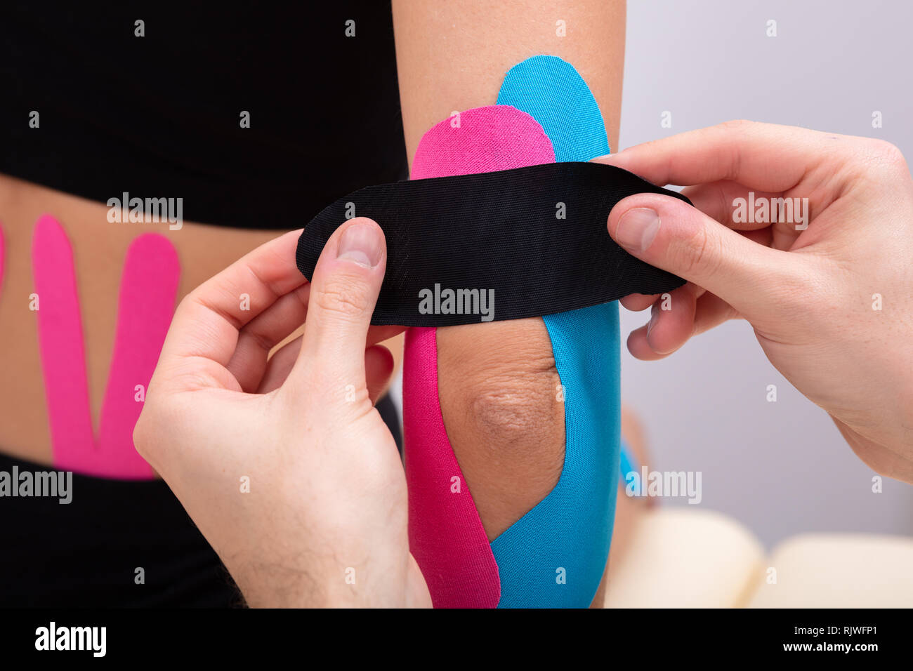 Close-up Of Physiotherapist Applying Kinesiology Tape On Patient's Elbow Stock Photo