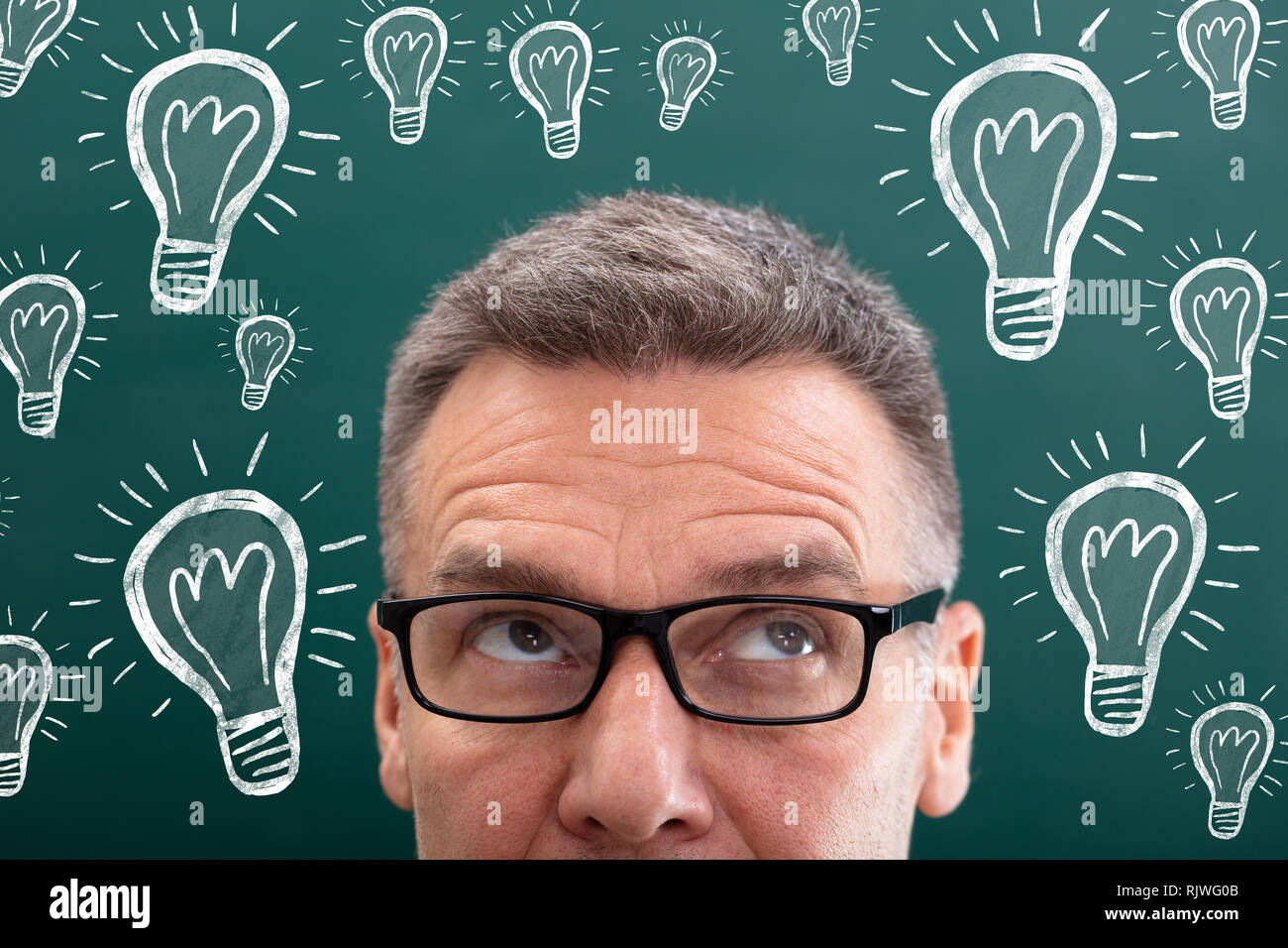 Thinking Mature Man Looking Up With Creative Light Bulb Drawn On Chalk Board Stock Photo