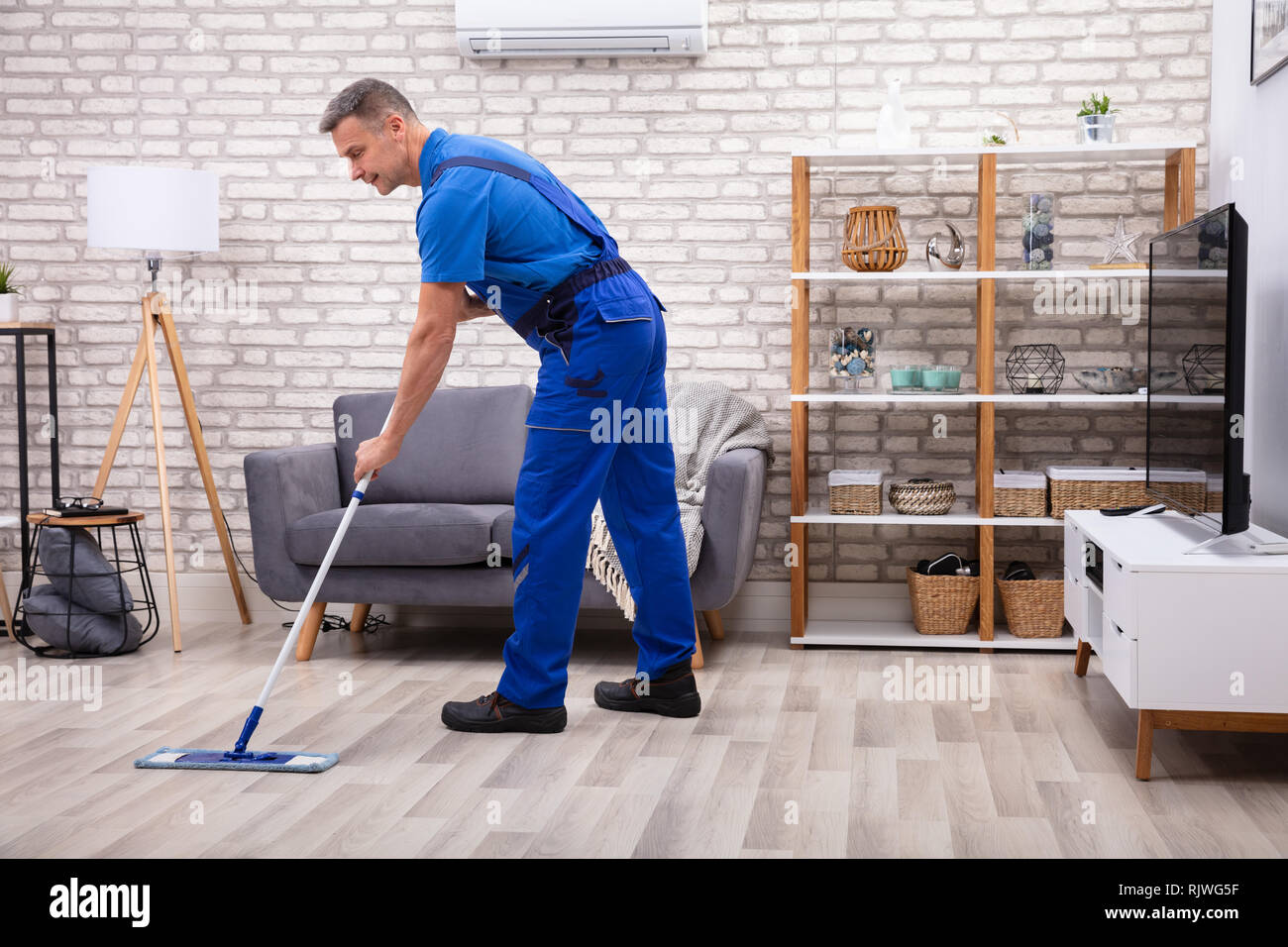 Mature Male Janitor Cleaning Floor With Mop At Home Stock Photo