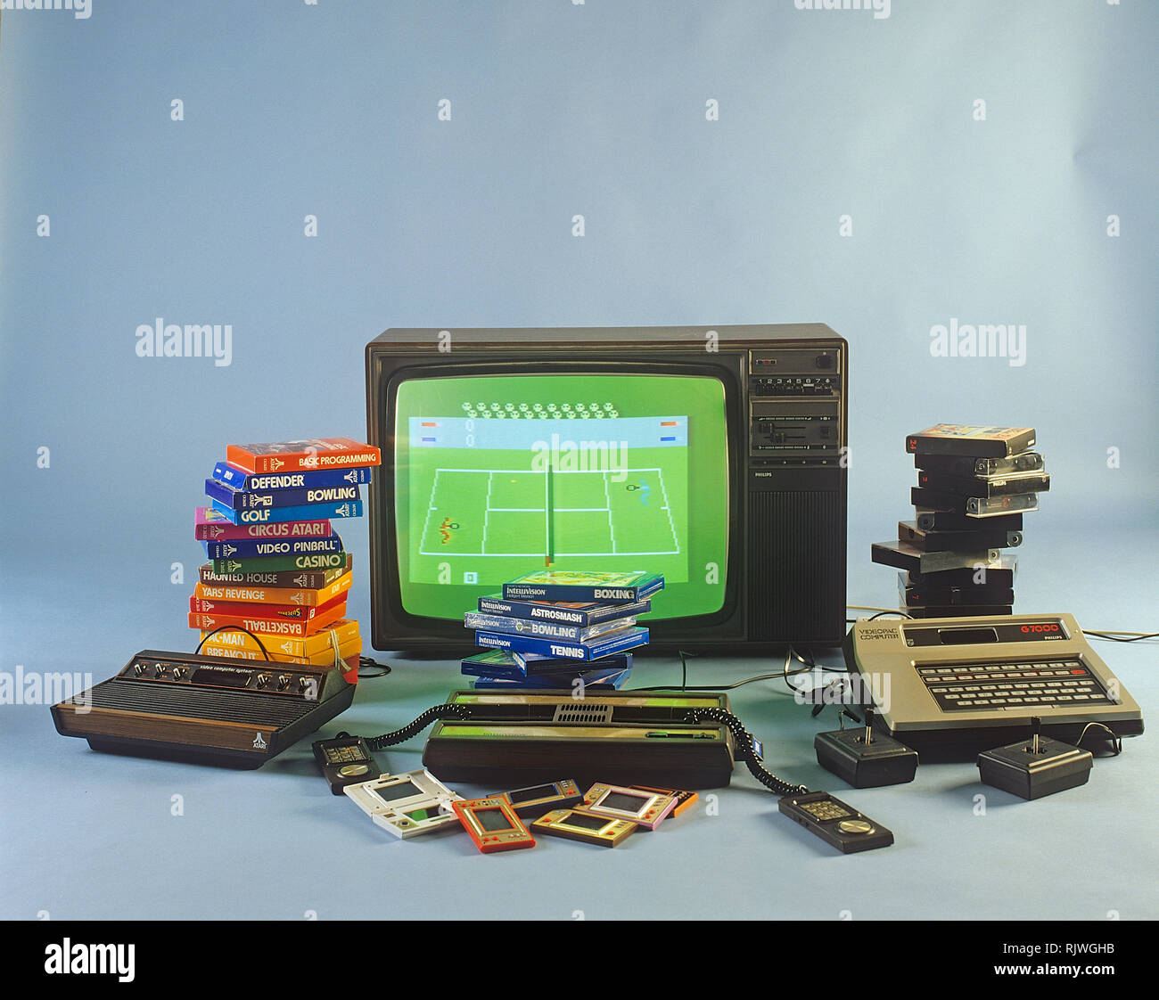 Home video games in the 1980s. A selection of the most popular game entertainment products in front of a television set. Atari, Intellivison, Philips Videopac G7000 and handheld consoles Game & Watch from Nintendo. 1980s. ref BV97-2 Stock Photo