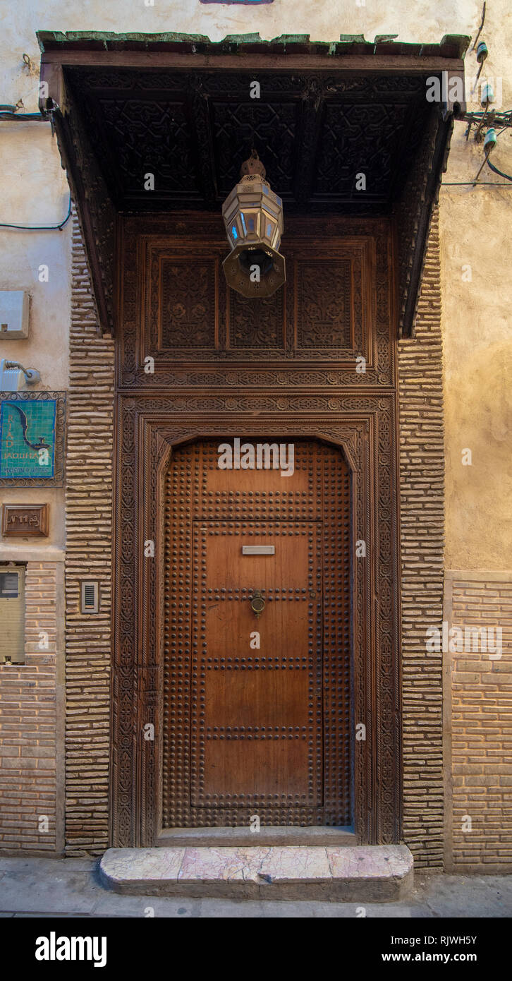 Traditional Moroccan style design of an ancient wooden entry door. In the old Medina of Fez , Morocco. Old riad door intricately carved, studded Stock Photo