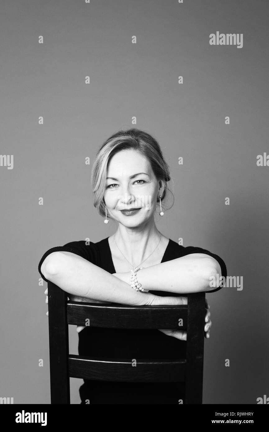 Portrait of beautiful woman in a black dress against grey background ...
