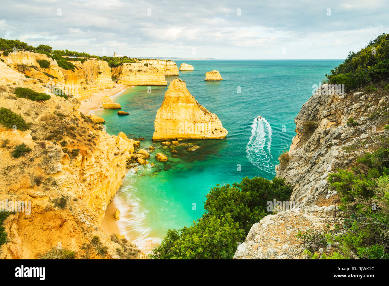 Boat sailing on sea by cliffs and rock formations, high level view, Praia da Marinha, Algarve. Portugal, Europe Stock Photo