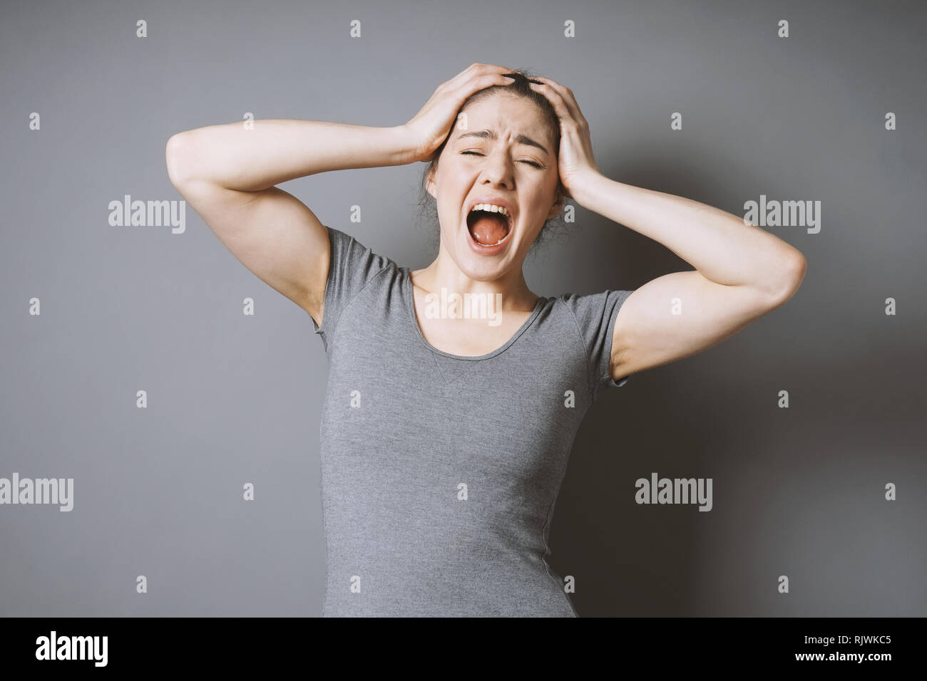 stressed young woman throwing a tantrum holding head screaming out