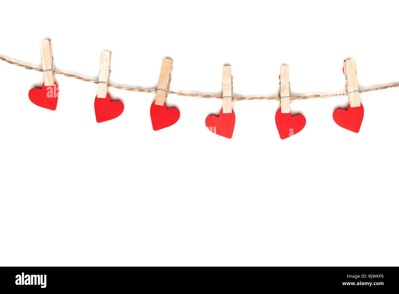 Clothes pegs and red paper hearts on rope isolated on white background ...