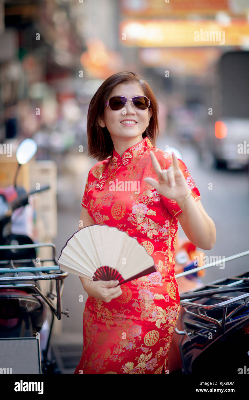 asian woman wearing chinese tradition clothes with chinese  bamboo fan toothy smiling face in yaowarat street china town of bangkok thailand Stock Photo