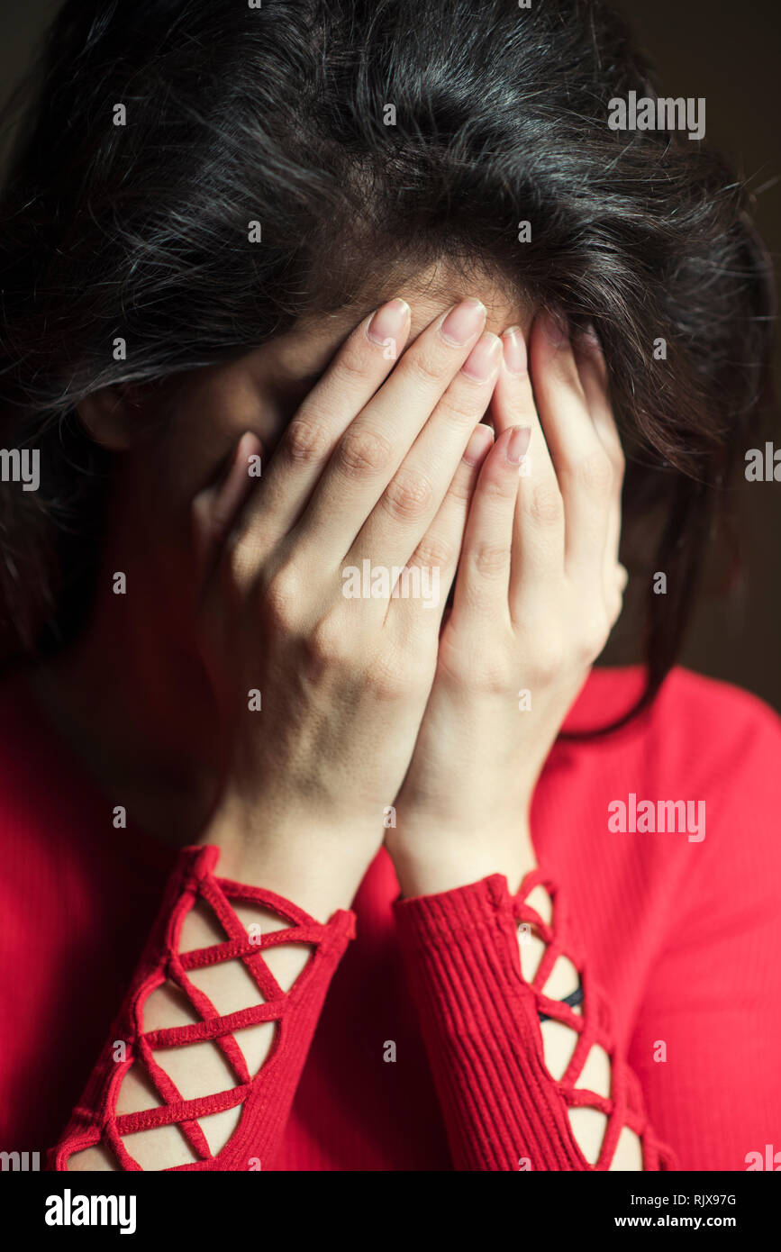 Young woman hiding face with hands crying Stock Photo