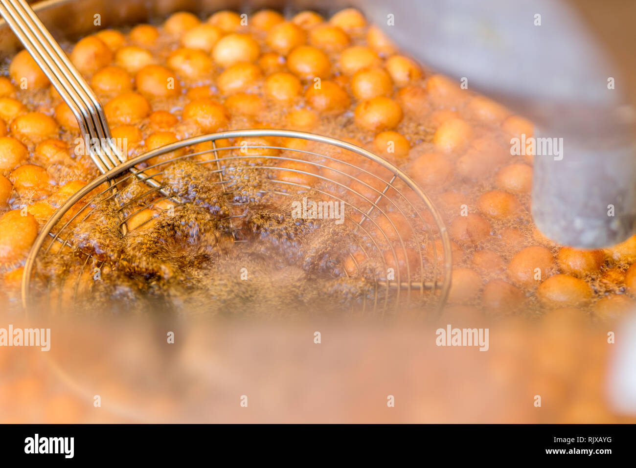 Sweet deep fried golden donuts doughnuts in hot boiling oil. Take away