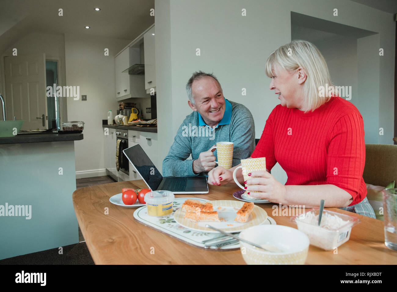 Mature couple are socialising over lunch and a cup of tea at home. Stock Photo