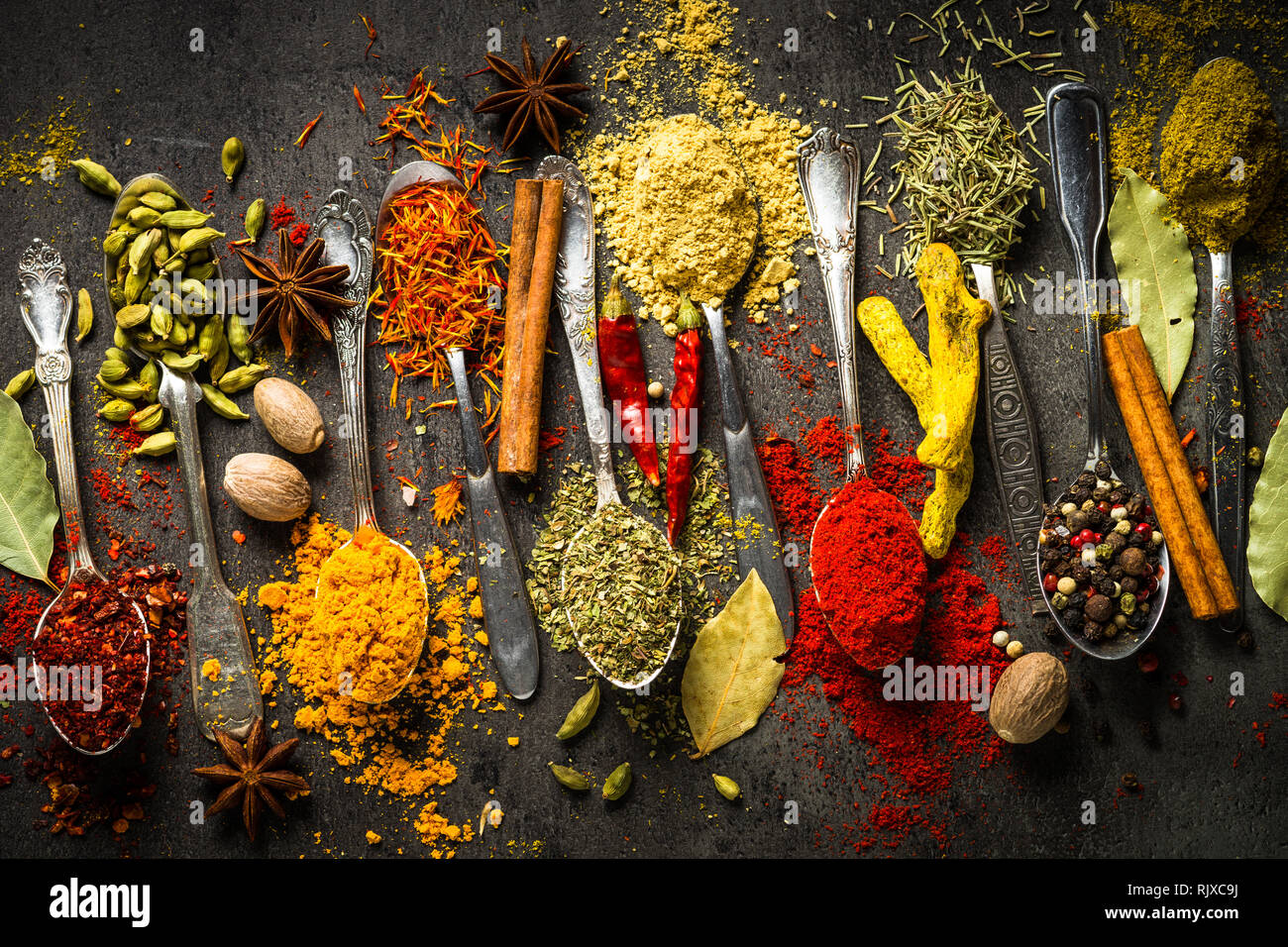 Composition of small spoons full of spices and condiments for cooking on a  black background Stock Photo - Alamy