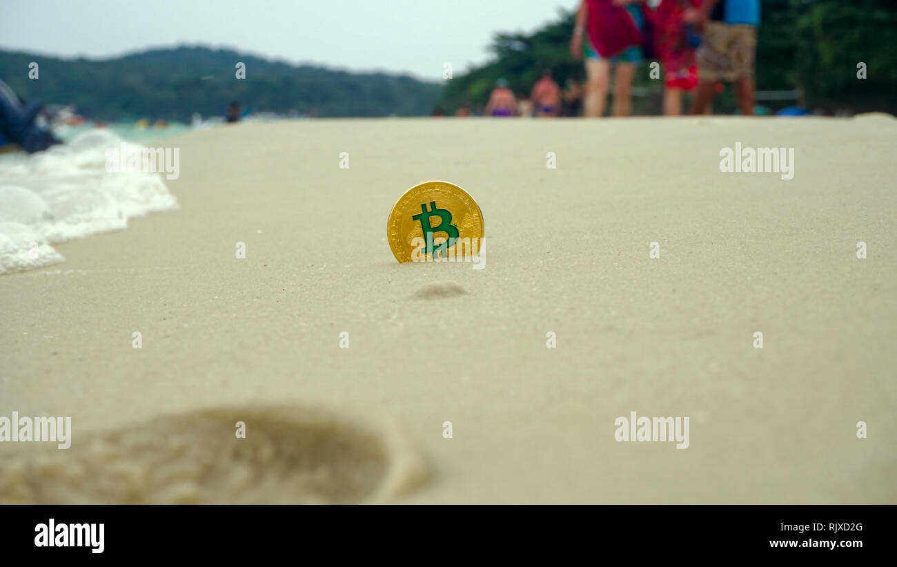 golden bitcoin crypto currency drop on the beach sand  by the sea at the summer day, copy space. Concept freelance, stock exchange. Stock Photo