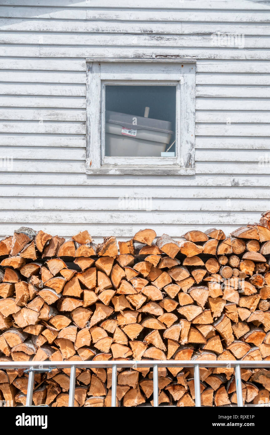 A pile of split logs stacked beside a house in Newfoundland ready for the winter. Stock Photo