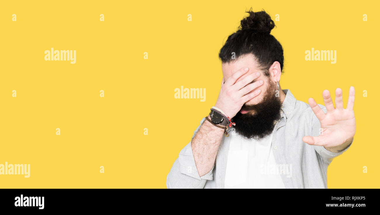 Young Man With Long Hair Beard And Earrings Covering Eyes With