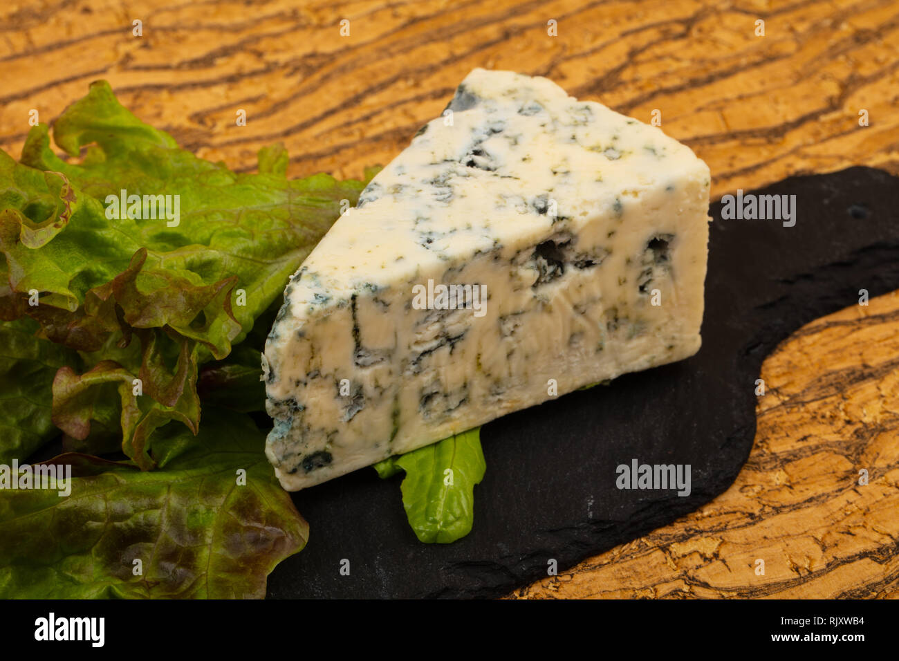 Blue cheese with salad leaves over board Stock Photo Alamy