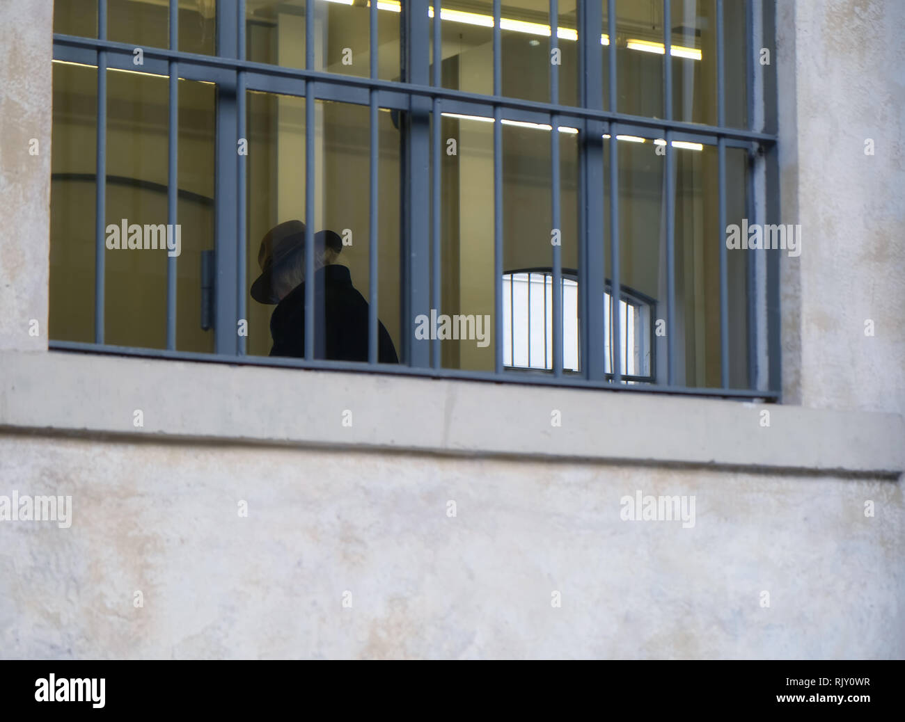 sad old senior man with hat inside building with barred windows - Law and justice concept Stock Photo