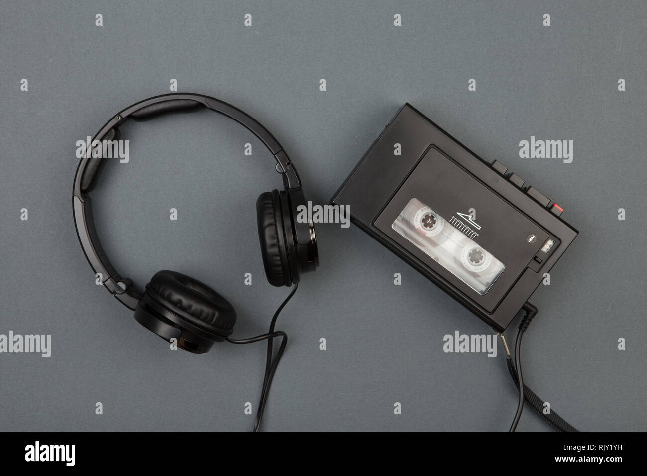 Retro cassette player with headphones on grey background, flat top view