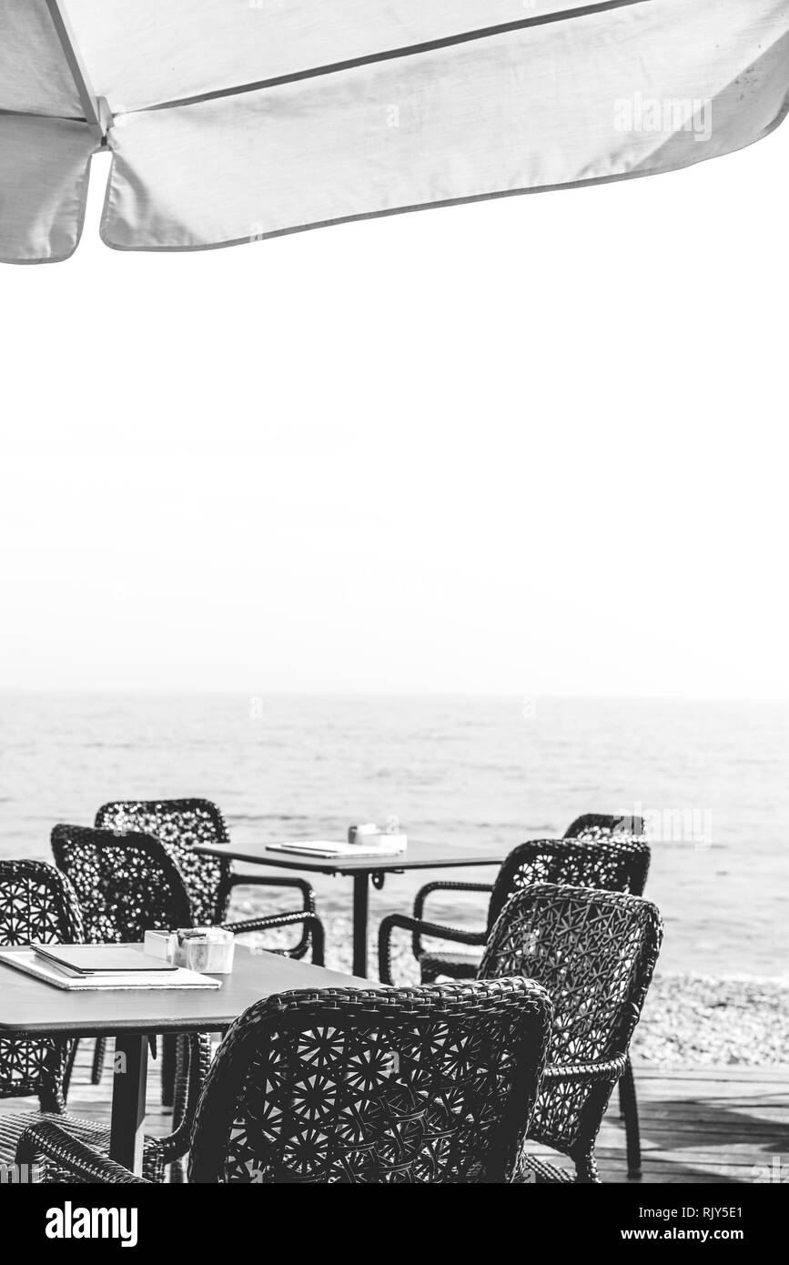 Wicker chairs by the empty outdoor restaurant tables at a seaside resort in summer Stock Photo