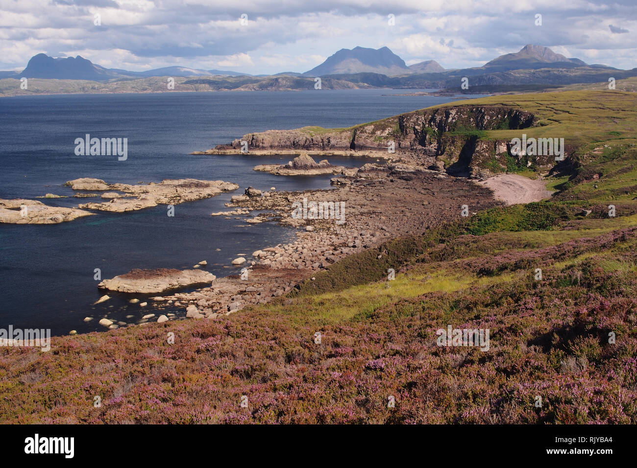 A view from the Coigach Peninsula over Enard Bay to Inverpolly Forest, Scotland on a sunny summer's day with mountains, sea and skyscape Stock Photo