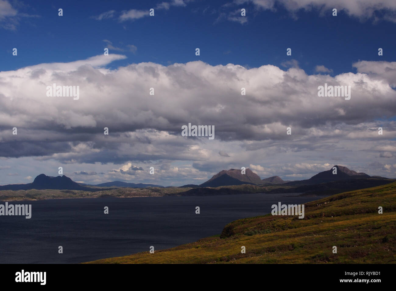 A view from the Coigach Peninsula over Enard Bay to Inverpolly Forest, Scotland on a sunny summer's day with mountains, sea and skyscape Stock Photo