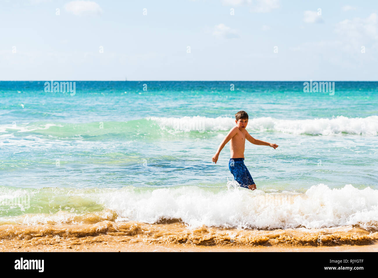 Boy playing by waters edge in blue shorts, Alvor, Algarve, Portugal, Europe Stock Photo