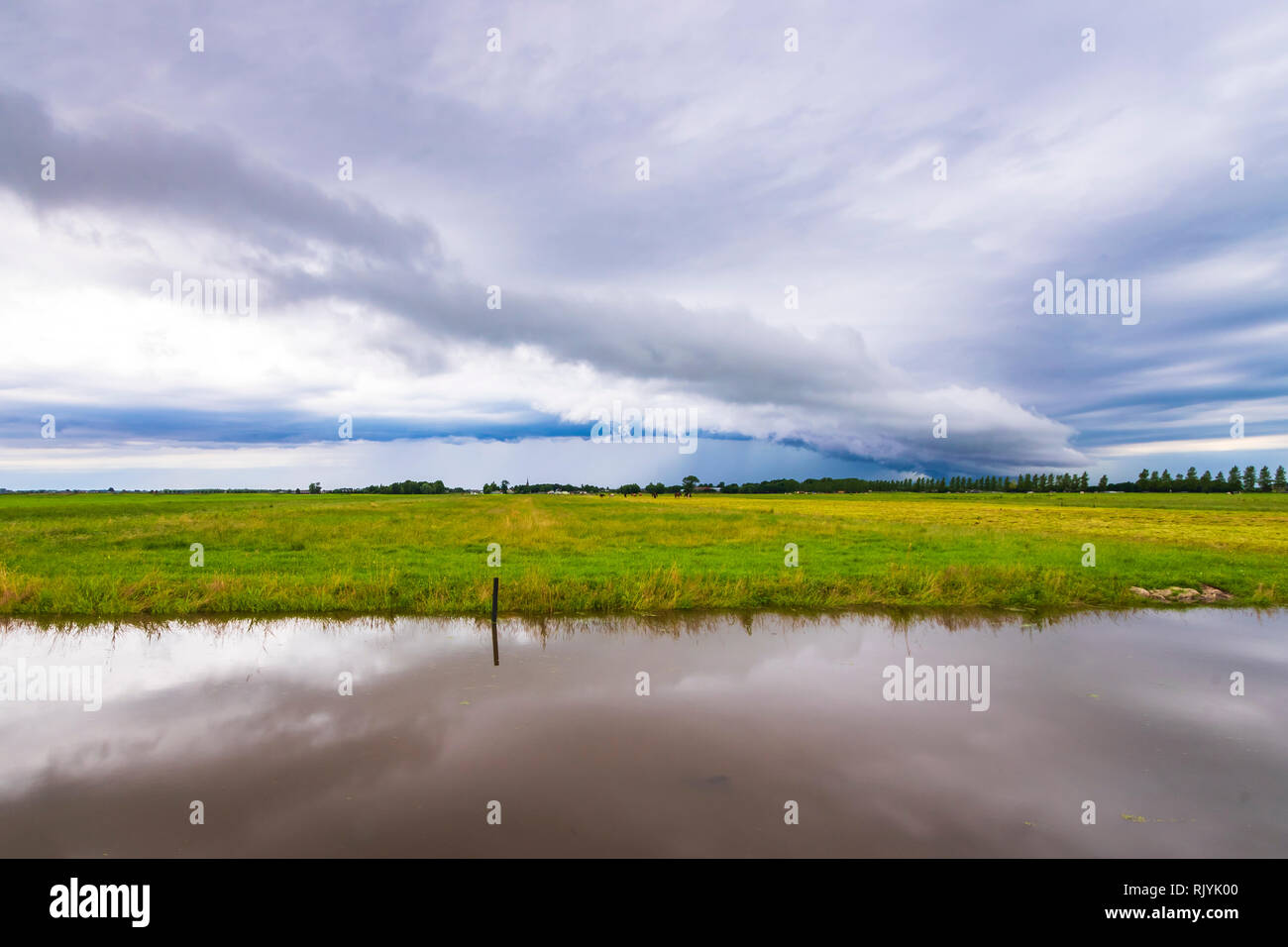 Shelf cloud and thunderstorm passing above green farmland and water in Zoetermeer, the Netherlands Stock Photo