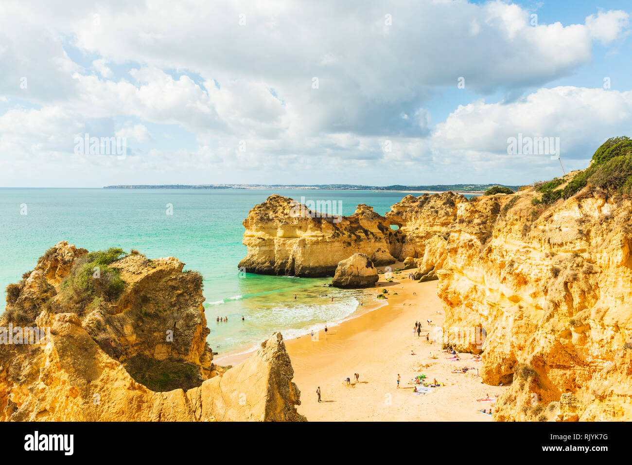 Sunbathers relaxing on sandy beach by sandstone cliffs, Alvor, Agarve, Portugal, Europe Stock Photo