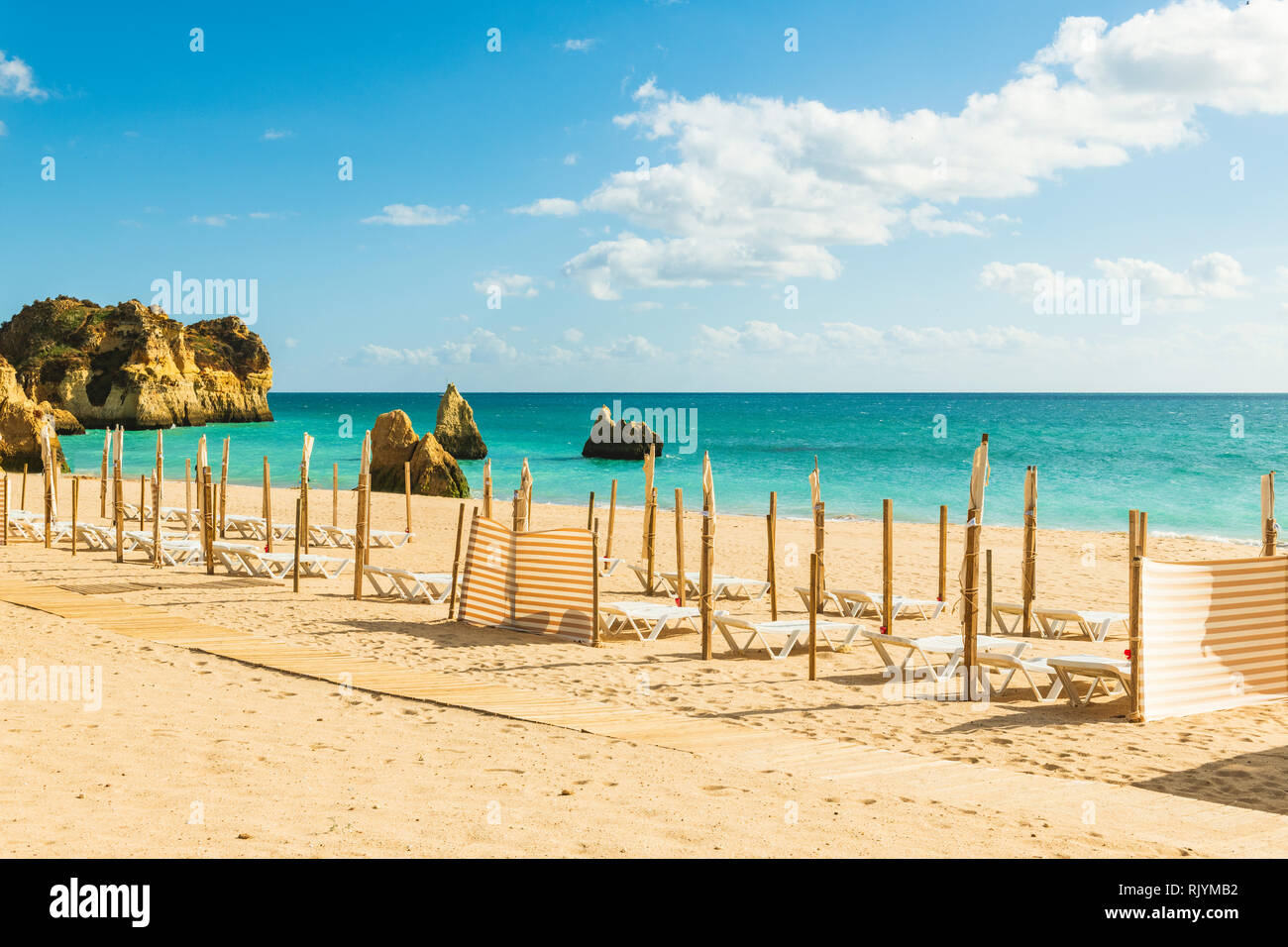 Row of empty sun loungers and windbreakers on sandy beach, Alvor, Algarve, Portugal, Europe Stock Photo