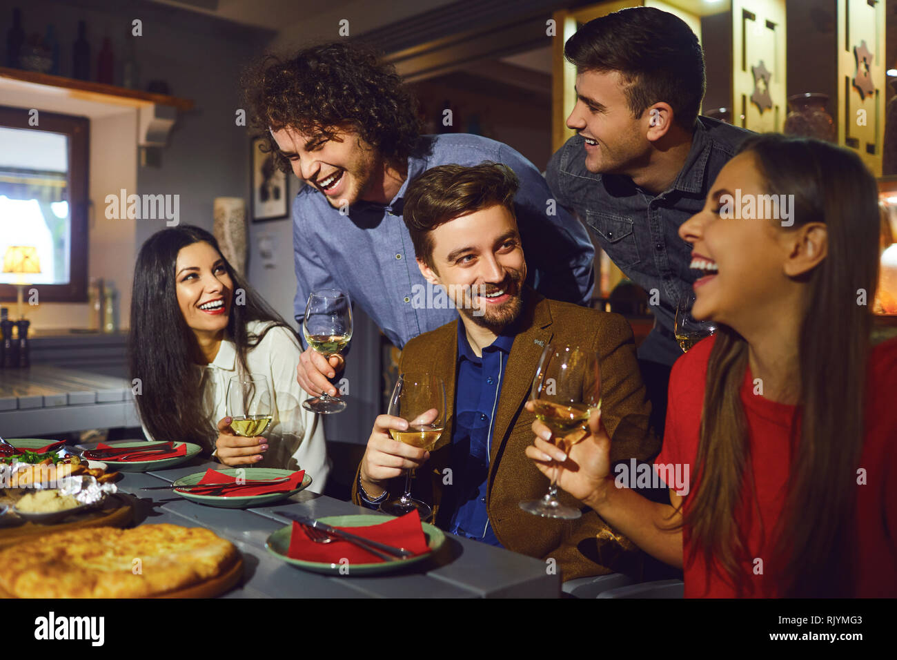Happy friends talk in a restaurant in the evening.  Stock Photo