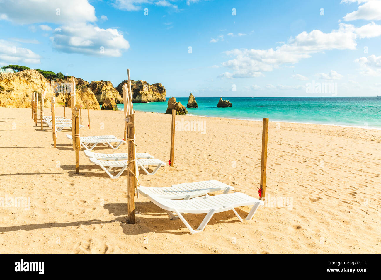 Row of empty sun loungers on sandy beach, Alvor, Algarve, Portugal, Europe Stock Photo