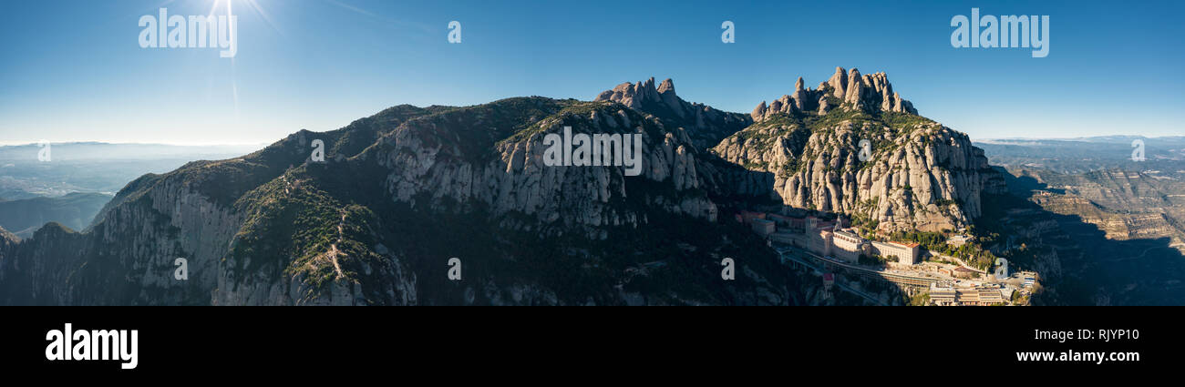 Aerial; wide panorama of famous abbey homonymous mountain range Montserrat; tourist attractions route of Spain; drone view of steep stone slope with m Stock Photo