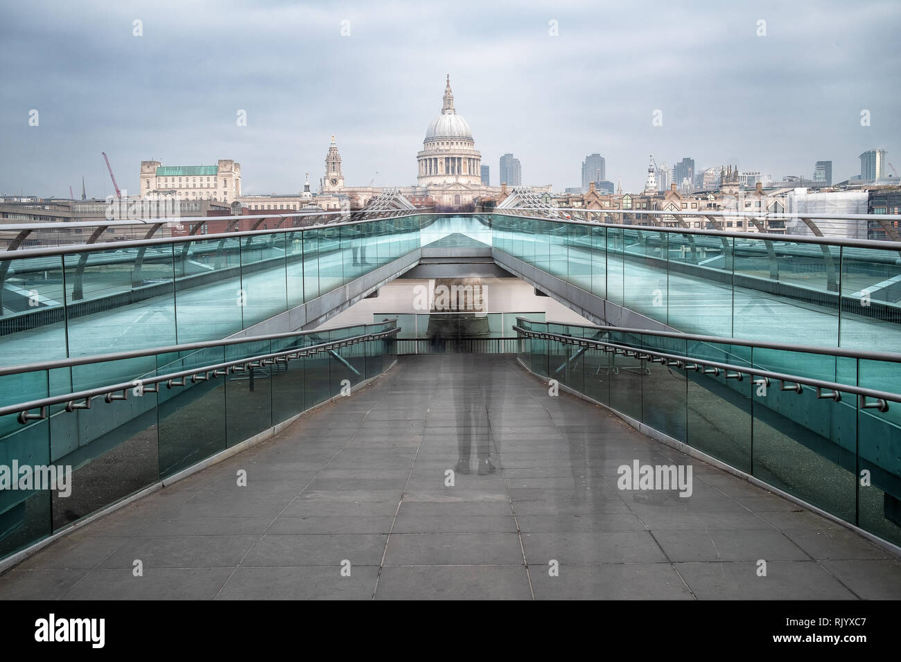 A 30 second exposure was used to blur some of the people on the Millennium Foot Bridge, London, England. It spans the River Thames towards St Pauls. Stock Photo