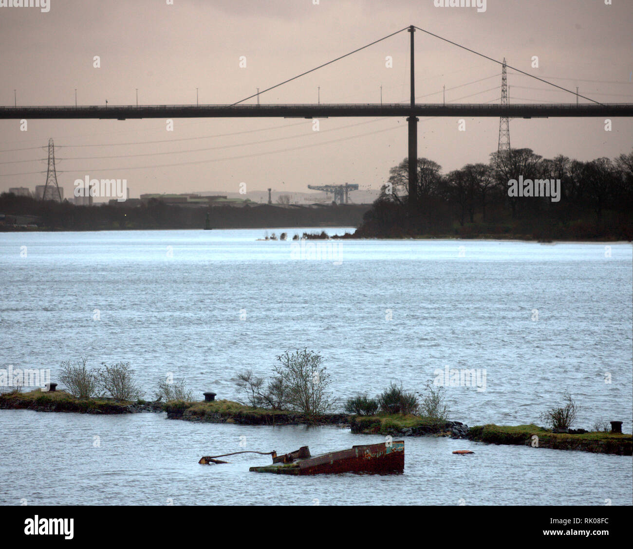 Glasgow, Scotland, UK  8th, February, 2019 UK Weather: Storm Erik brought strong winds and rain all day and the Erskine bridge was closed with a warning for high sided vehicles. In foreground Graving Dock at high tide on Bowling harbour on the Clyde with a distant Glasgow about to be hit with the storm. Credit Gerard Ferry/Alamy Live News Stock Photo