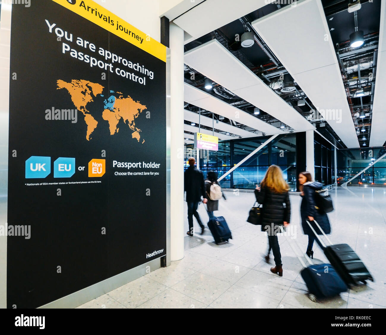 London Heathrow, UK, Feb 5, 2019: Passenger walks past sign prior to immigration passport control pointing towards queues for UK, EU and Non-EU Stock Photo