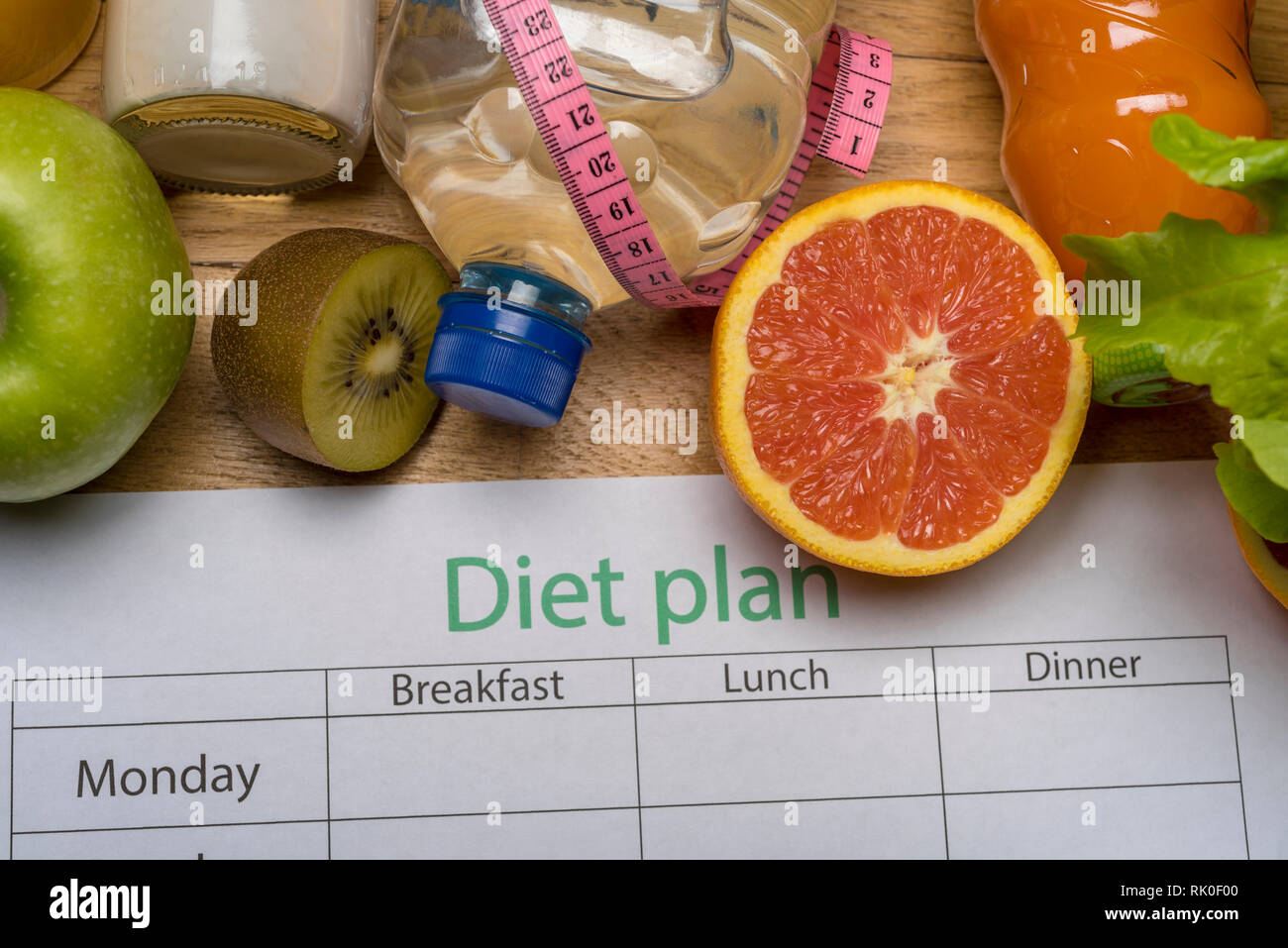Diet plan, tape measure, water, diet of fresh fruits on the wooden floor. weight loss and ...